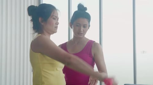 Young asian woman lift dumbbell for exercise with effort and strong for muscle hands with coach.