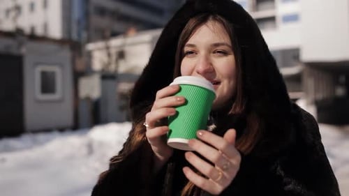 Woman Drinks Coffee Outdoors in Winter City