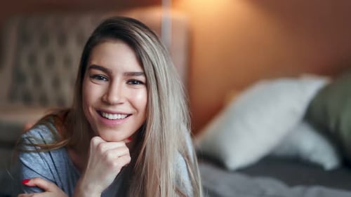 Smiling Young Woman Relaxing on Bed at Home