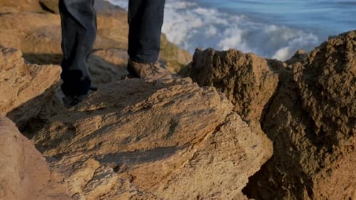 Man Walking on Rocks Near the Ocean