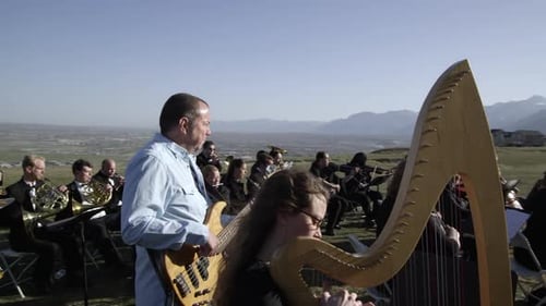 Orquesta tocando al aire libre en una colina con vistas a un valle