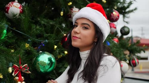 Young Woman Smiling with Christmas Tree in Urban Setting