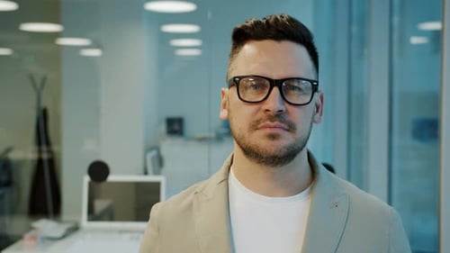 Zeitlupe eines ernsthaften Mannes mittleren Alters mit Brille, der abends im Büro steht
