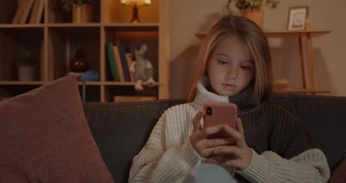 Crop View of Young Pretty Girl Scrolling Smartphone Screen While Sitting on Sofa at Home