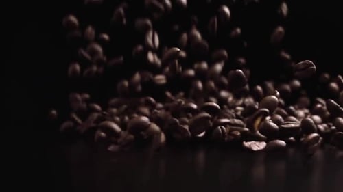 Aromatische Kaffeekörner fallen gegen braunen Hintergrund