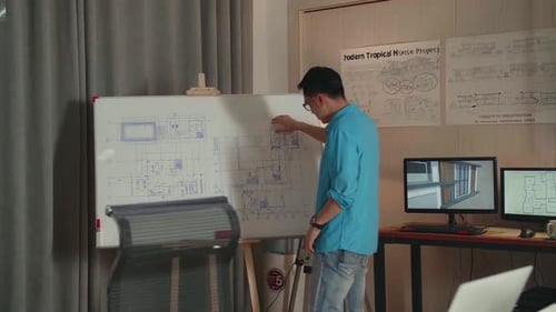Asian Man Engineer Typing On A Laptop And Walking To Draw The Blueprint On The Whiteboard