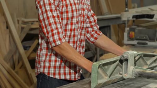 Happy Male Carpenter Posing with a Piece of Wood at His Workshop