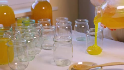 Pouring Yellow Liquid into Glass Jar