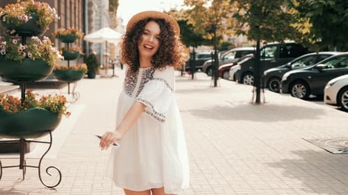 Woman Dancing in White Dress on City Sidewalk