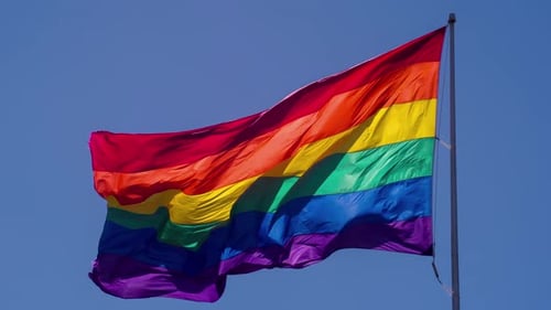 LGBTQ Pride Flag Waving Against Blue Sky