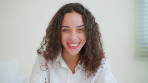 Smiling Woman with Curly Hair in a Bright Room