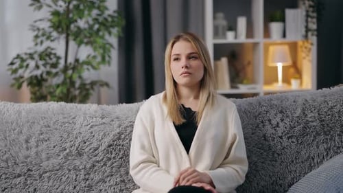 Woman Sitting on Sofa Holding Forehead