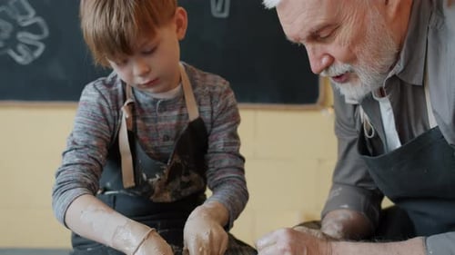 Grandfather Teaching Boy Pottery on Wheel