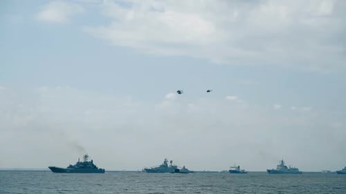 Helicopter Silhouettes Fly Over Naval Vessels at Parade