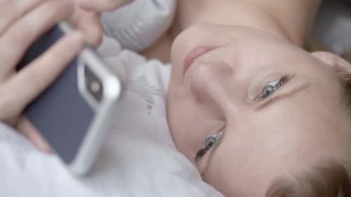 Woman Lying in Bed Using a Smartphone