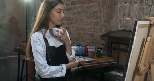 Woman Painting on Canvas and Drinking Coffee