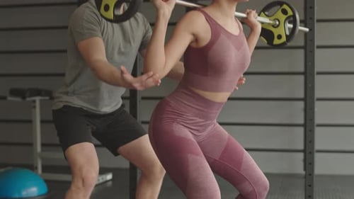 Coach Helping Female Athlete Doing Squats