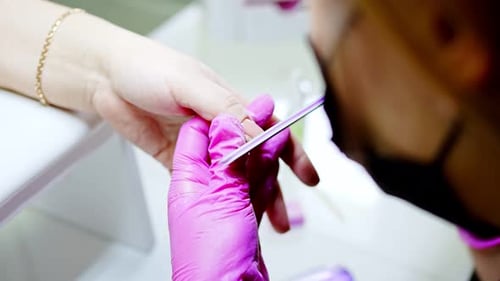 Nail Technician Filing Nails in Beauty Salon