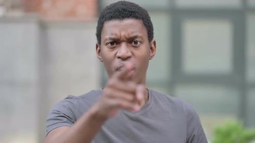 Upset Adult Points to Camera in Urban Setting