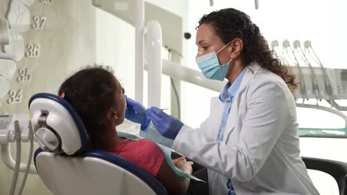 Masked Dentist Examining Teeth of Child Patient