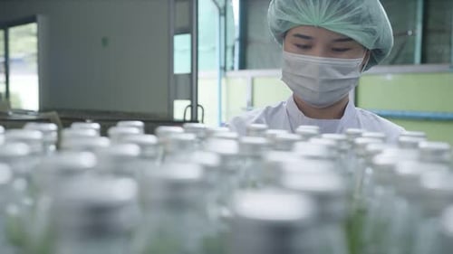 Superviseur asiatique inspectant une chaîne de production de bouteilles de boissons aux herbes