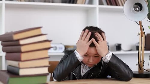 Tired Child Sitting at Desk with Books