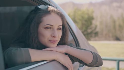 Lady Leans Out of Car Window and Looks at Mountain Landscape