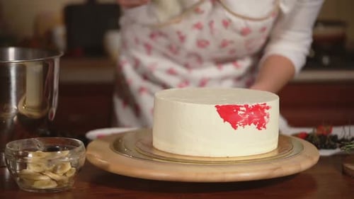 Woman Decorating Cake with Red Frosting in Kitchen