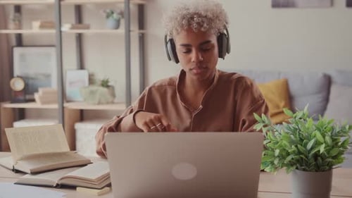Young Woman Studies at Home with Laptop and Books