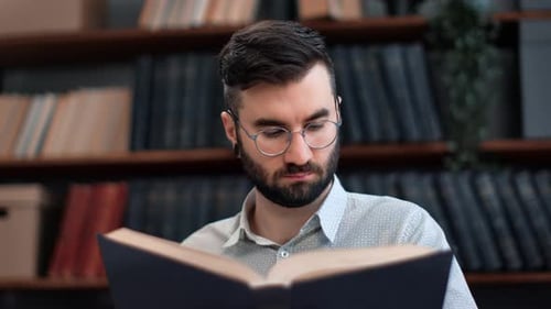 Modern Bearded Man White Collar Shirt Reading Vintage Interesting Paper Book Turning Page at Library