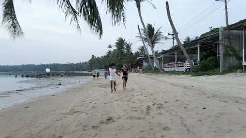 Happy Interracial Couple Running Holding Hands at a Tropical Island Beach at Sunset Aerial Front