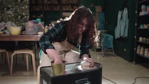 A Woman Forms Clay on a Potter's Wheel in the Art Studio