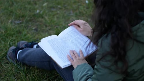 Beautiful woman on a cloudy day reads a book in the park