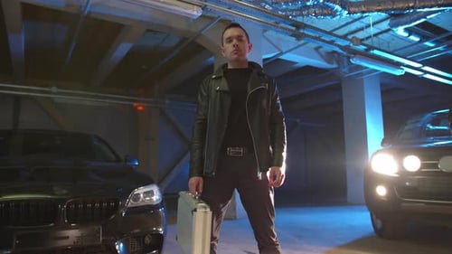 Un criminel se tient sur le parking avec une valise