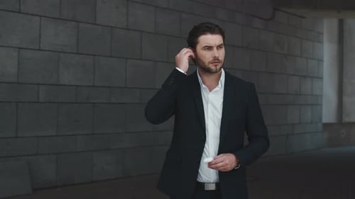 Man in Suit Inserts Wireless Earbud
