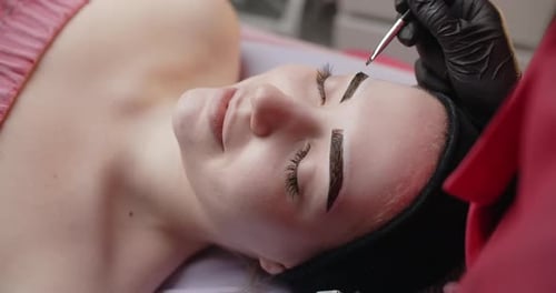 Una esteticista hace tintes de cejas con henna para la mujer joven Procedimientos cosmetológicos y cuidados de belleza