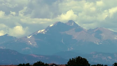 Ein entfernter felsiger Berggipfel verwittert, während die Wolken in diesem Zeitraffer überziehen.