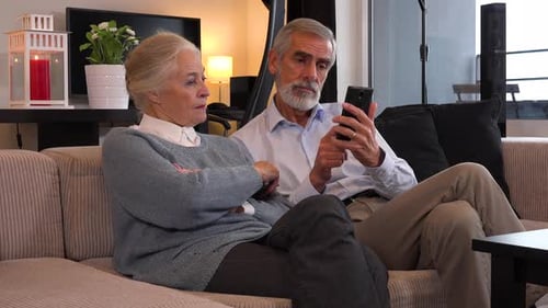 Senior Couple Relaxing with Smart Phone on Couch