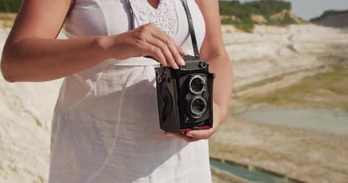 A Woman Holds a Camera and Photographs the Landscape