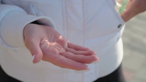 Woman applies hand sanitizer on city street