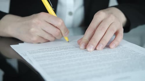 Hands Signing Legal Document with Yellow Pen