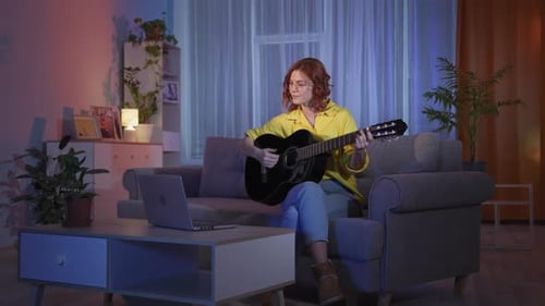 Young Woman Playing Guitar in Living Room