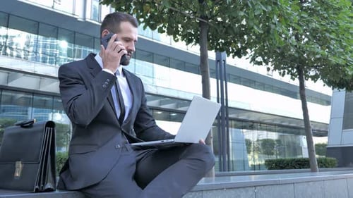 Working Businessman Talking on Phone Outside Office