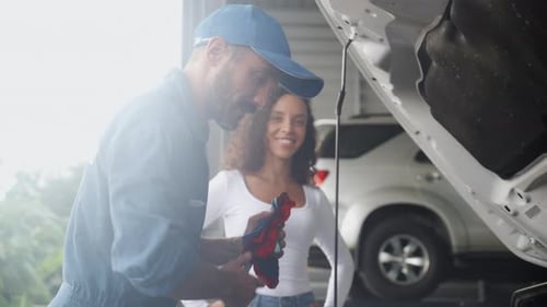 Young man mechanic talking with customer for examining trouble and repairing engine of car.