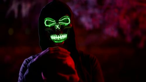 Person Wearing Glowing Skull Mask Holding Pumpkin