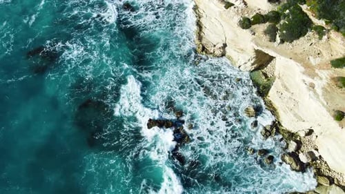 Sea Washes the Rocky Shore Above Aerial Shot Flying Over Coastline Cliffside with Blue Pure Water