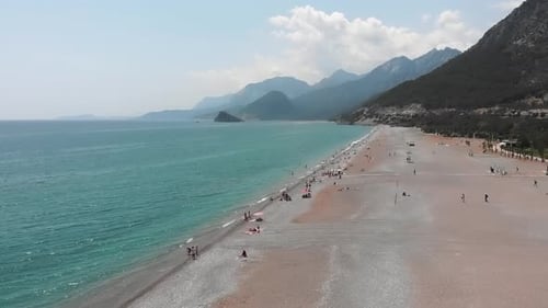Wide sandy beach with mountains on background.