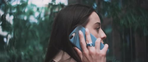 Mulher no telefonema desliga e caminha na direção oposta