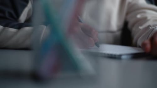 Child Writing in Notebook with Black Pen Indoors