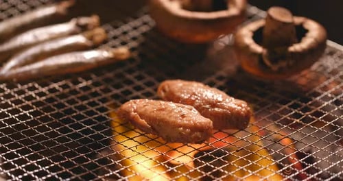 Barbecue mit Hühnerflügel, Champignons und Lodde auf gegrilltem Netz
